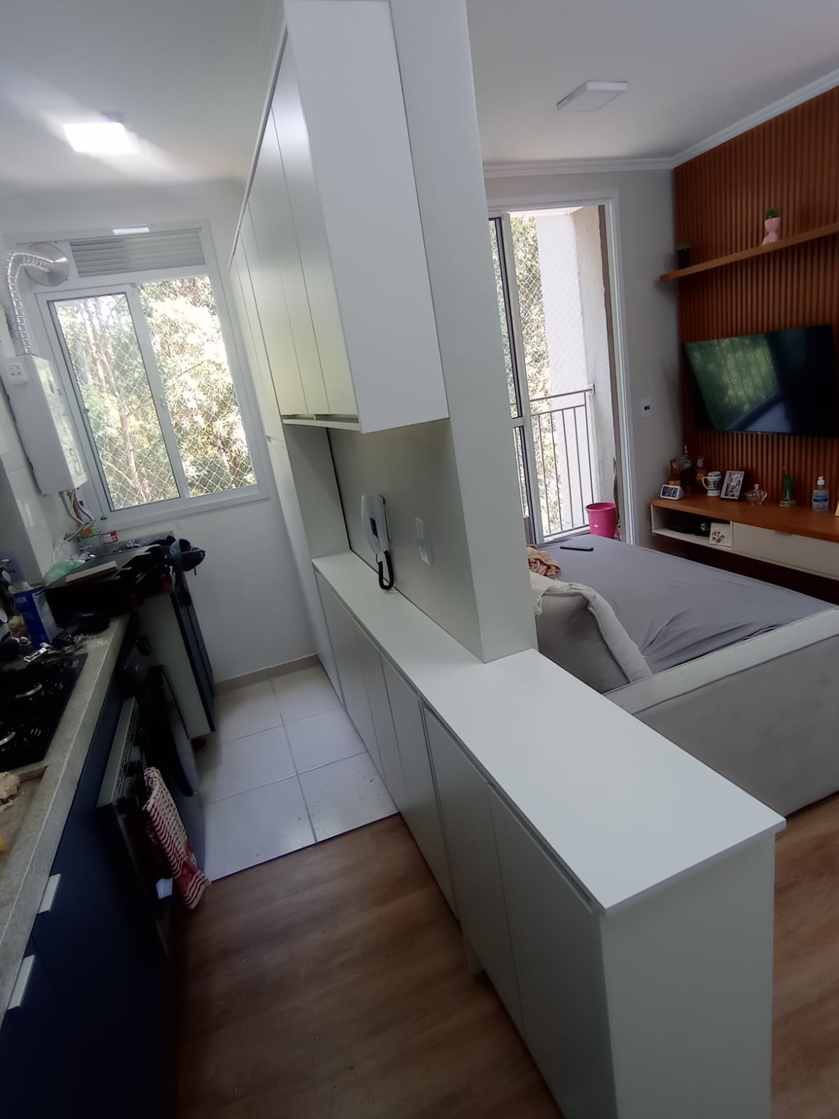 Cozinha integrada com balcão e painel de TV em madeira